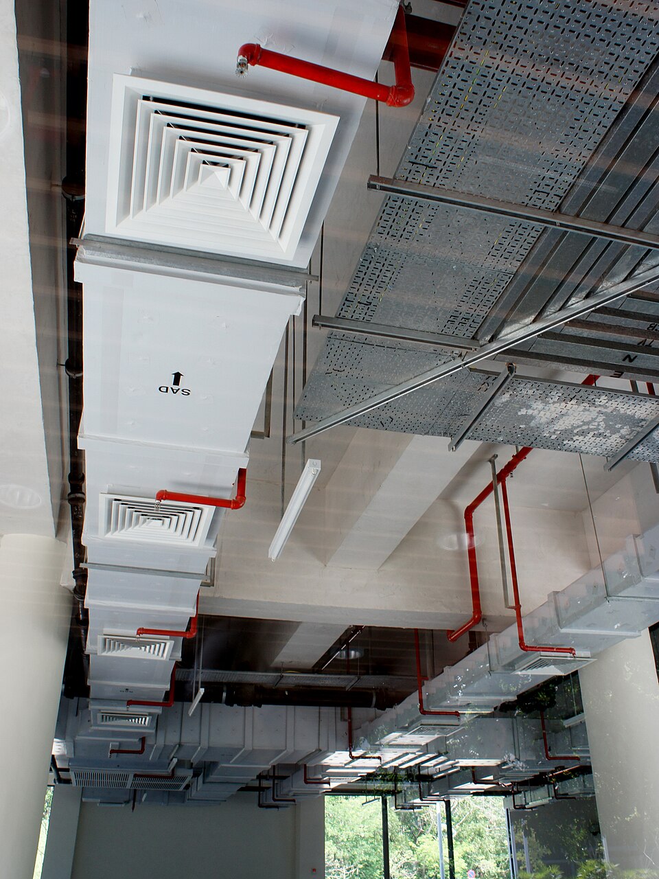 Exposed ceiling HVAC ductwork, diffusers, fire sprinkler piping and cable trays in a building interior.